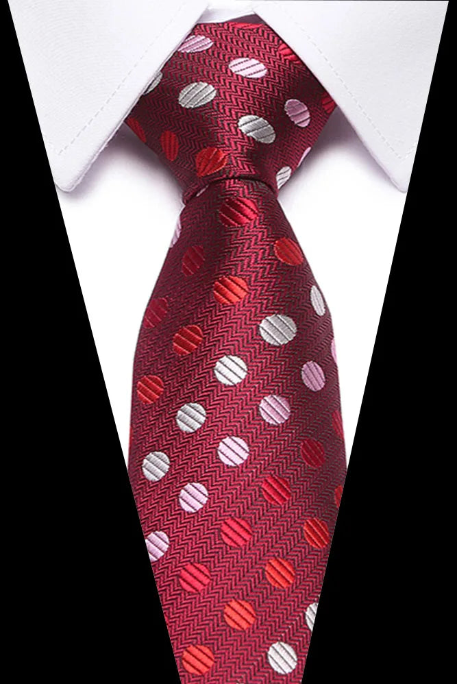 A close-up of a men's silk jacquard tie in red with silver polka dots, tied against a white shirt.