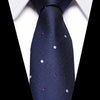 A dark blue silk jacquard tie with scattered silver and pink sequins worn against a white shirt.