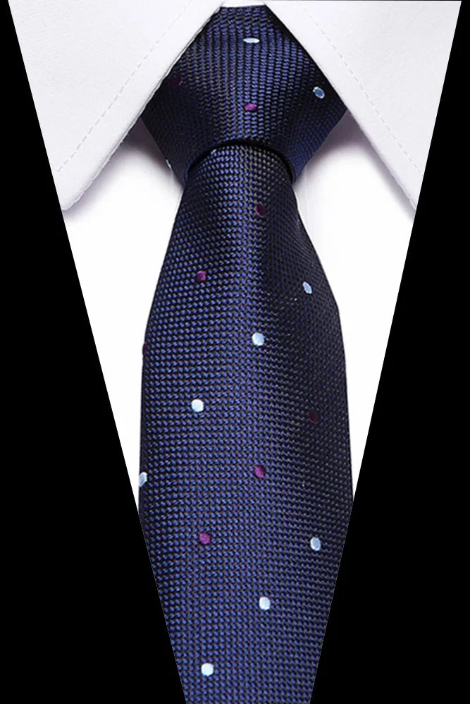 A dark blue silk jacquard tie with scattered silver and pink sequins worn against a white shirt.