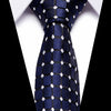 A dark blue silk jacquard tie with white geometric patterns tied in a knot against a white shirt.
