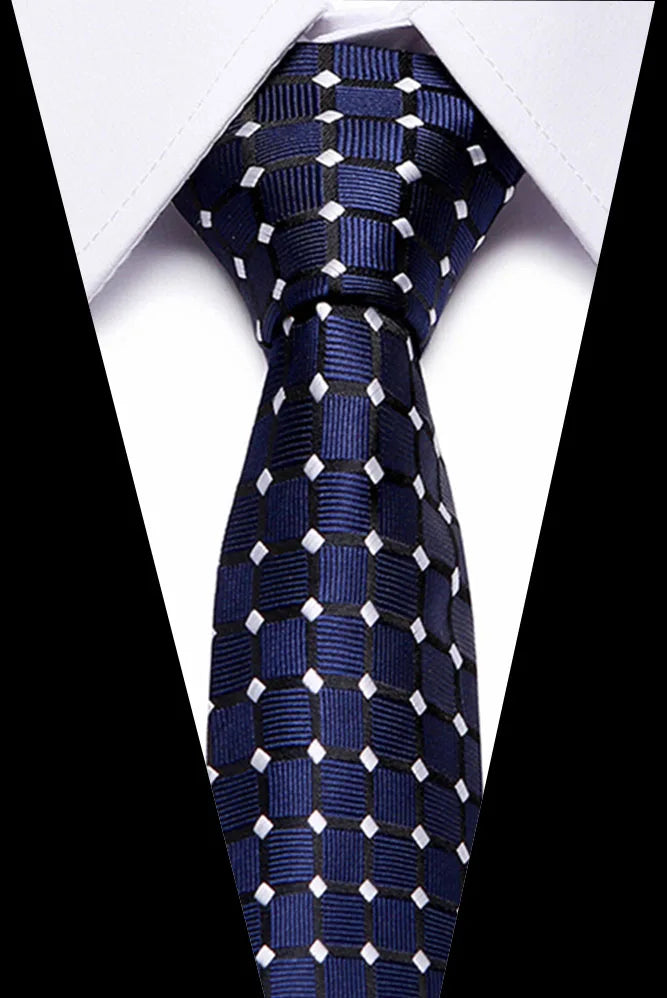 A dark blue silk jacquard tie with white geometric patterns tied in a knot against a white shirt.