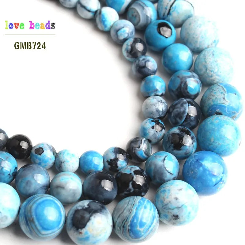 A close-up of natural sky blue fire agate spacer beads in various shades and sizes.