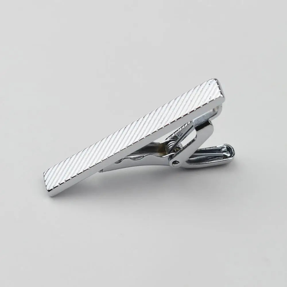 Primer plano de un clip de prendedor de corbata de acero inoxidable plateado con superficie texturizada.