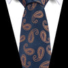 A dark blue silk jacquard tie with an ornate gold paisley pattern worn under a white shirt.
