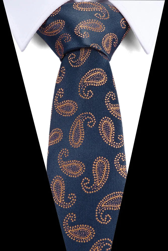 A dark blue silk jacquard tie with an ornate gold paisley pattern worn under a white shirt.