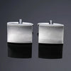 A pair of silver square cufflinks displayed against a dark gray background.