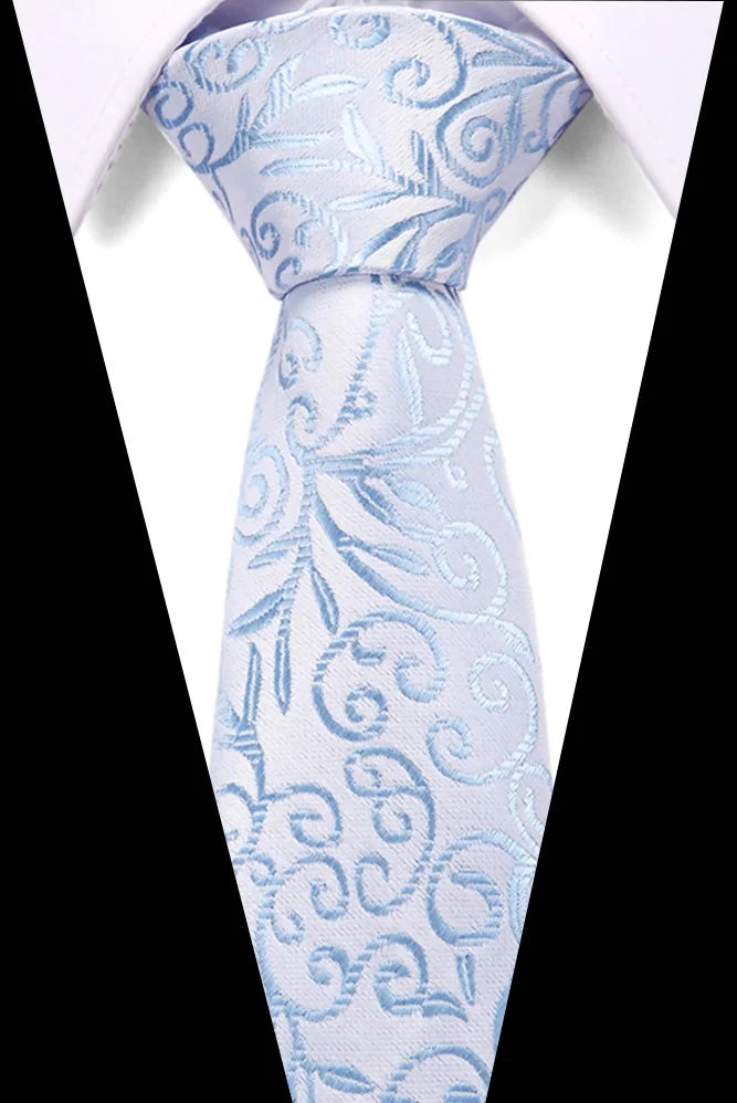Light blue silk jacquard tie with swirling floral patterns worn against a white shirt.