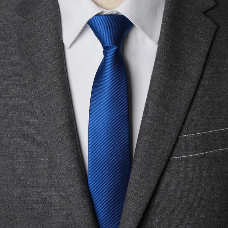 A close-up of a navy blue striped tie worn with a white shirt under a gray suit jacket.