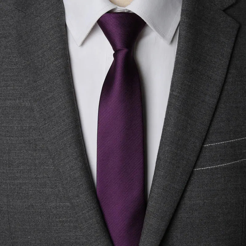 A close-up of a purple striped tie worn under a gray suit jacket and white shirt.