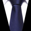 A close-up of a dark blue silk jacquard tie worn against a white shirt.