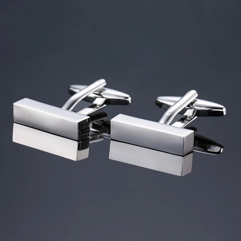 A pair of silver-toned men's classic square cufflinks displayed against a dark gray background.