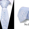 Light blue silk jacquard tie with intricate scrollwork pattern folded and displayed on a white shirt collar.