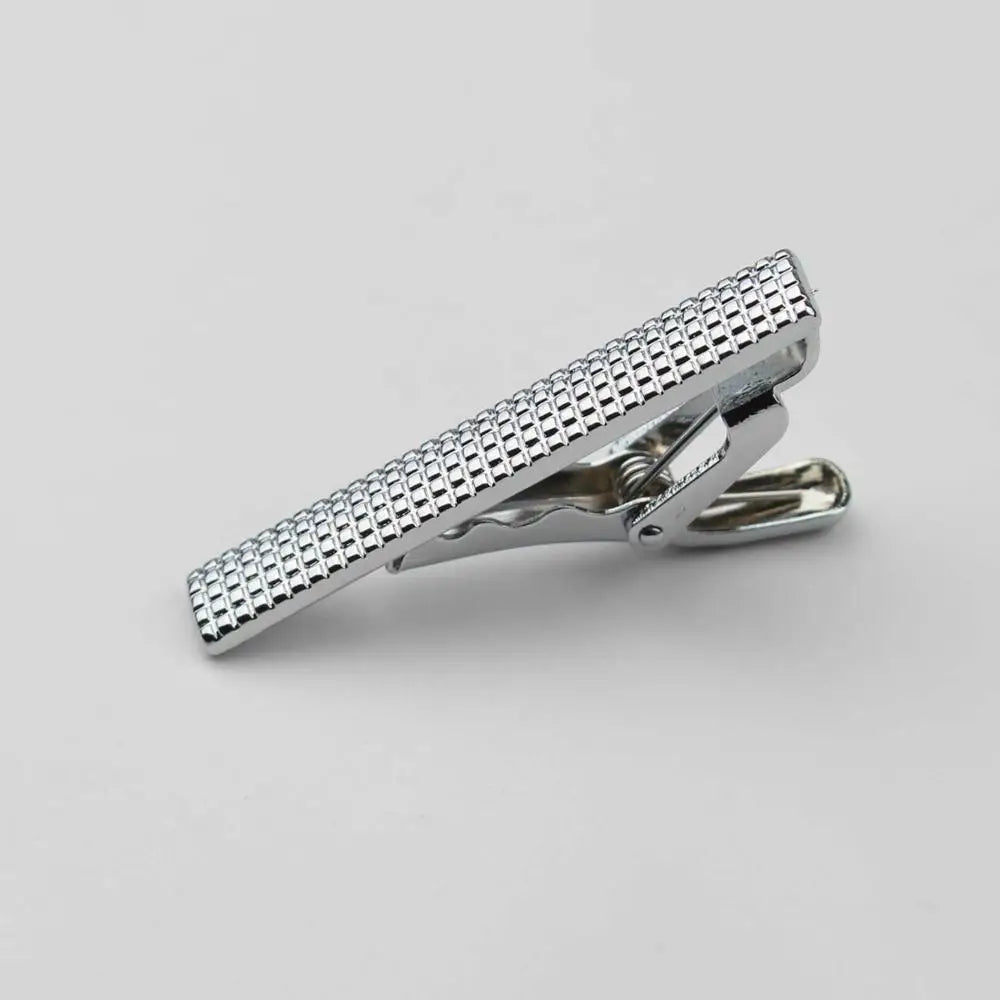 Primer plano de un sujetador de corbata de acero inoxidable para hombre con acabado texturizado.