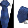 A dark blue silk jacquard tie folded and displayed against a white shirt background.