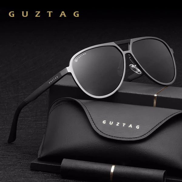 A pair of black GUZTAG sunglasses resting on a black leather case.