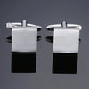 A pair of silver square cufflink holders with a metal bar and a square plate.