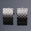 A pair of silver-toned square cufflinks with a checkered pattern, displayed against a dark gray background.