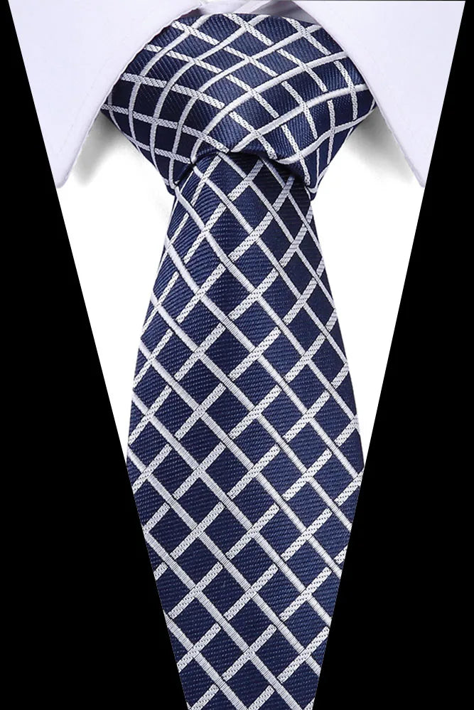 Navy blue silk jacquard tie with a white checkered pattern worn against a white shirt.