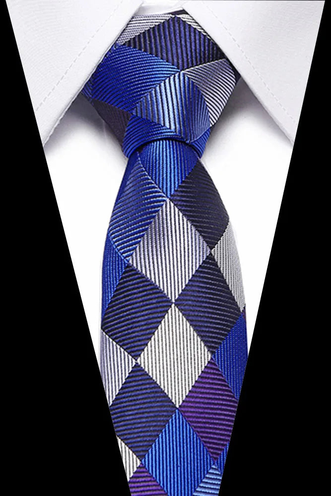 A men's silk jacquard tie featuring a blue, silver, and purple diamond pattern worn against a white shirt.