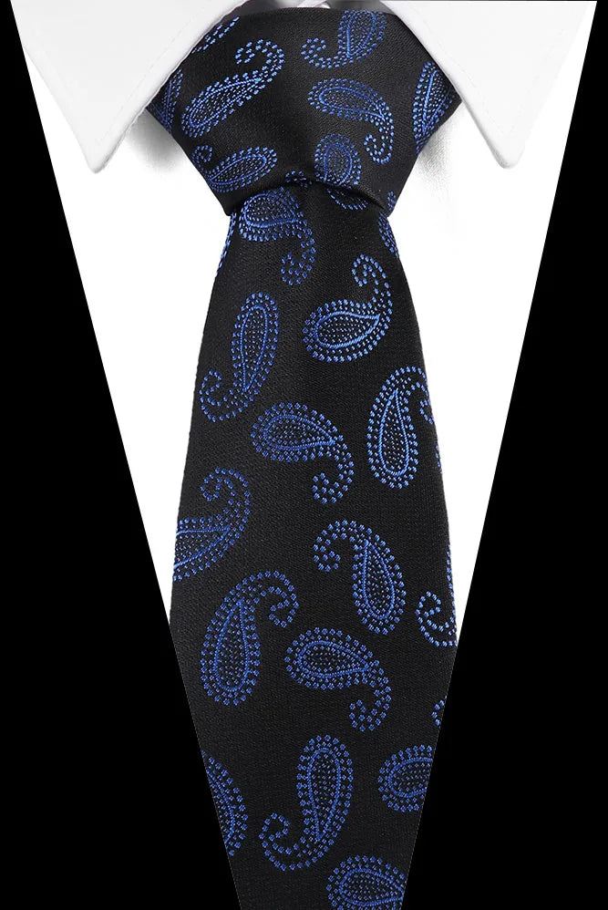 Black silk jacquard tie with blue paisley pattern worn under a white dress shirt.