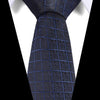 A dark blue silk jacquard tie is shown against a white shirt background.