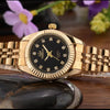 A luxury golden quartz wristwatch with a gold-tone bracelet rests on a dark stone surface.