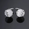 A pair of silver cufflinks featuring a checkered pattern on a circular face.