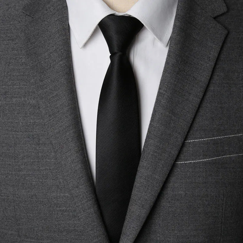A close-up of a dark gray suit jacket with a white shirt and black tie.