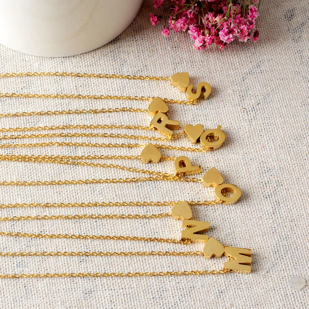 Goldene Initialen-Herz-Kette mit verschiedenen Buchstaben und Herzen an einer zarten Kette