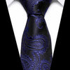 A close-up of a dark blue silk jacquard tie with intricate floral patterns against a white shirt.