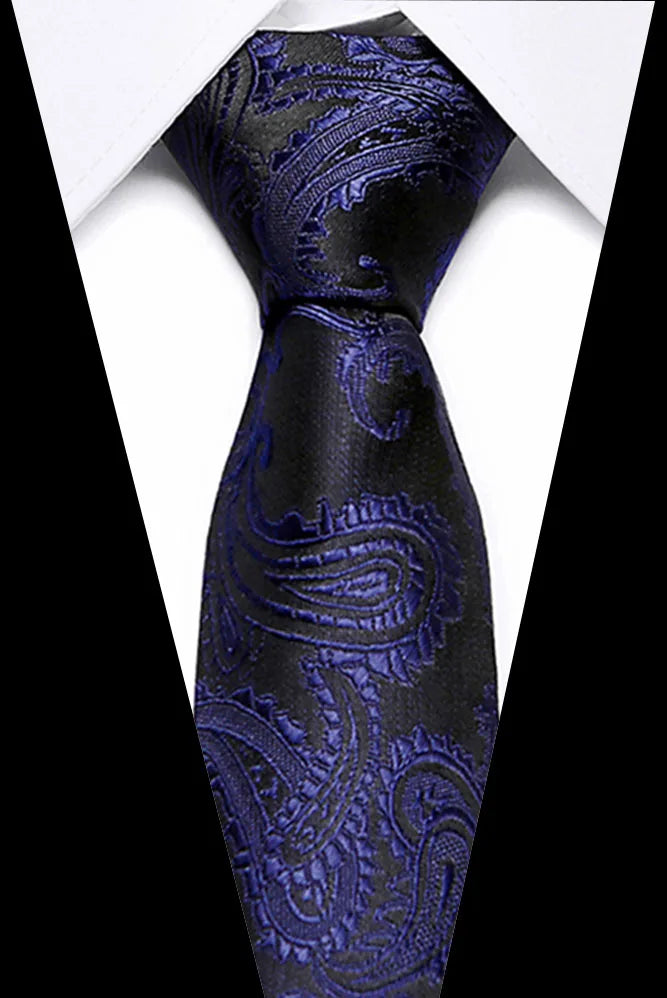 A close-up of a dark blue silk jacquard tie with intricate floral patterns against a white shirt.
