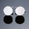 A pair of silver cufflinks with round, polished surfaces displayed against a dark background.