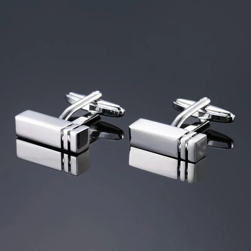A pair of silver-toned men's classic square cufflink accessories displayed on a dark gray background.
