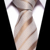 Close-up of a beige and gold striped silk jacquard tie knotted in a Windsor knot against a white shirt.