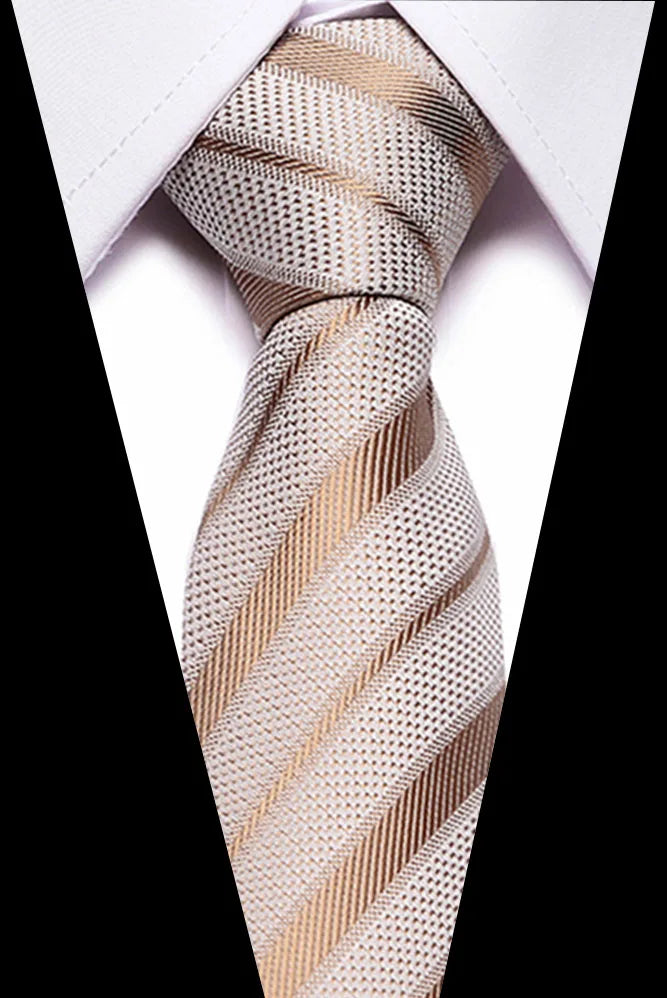 Close-up of a beige and gold striped silk jacquard tie knotted in a Windsor knot against a white shirt.