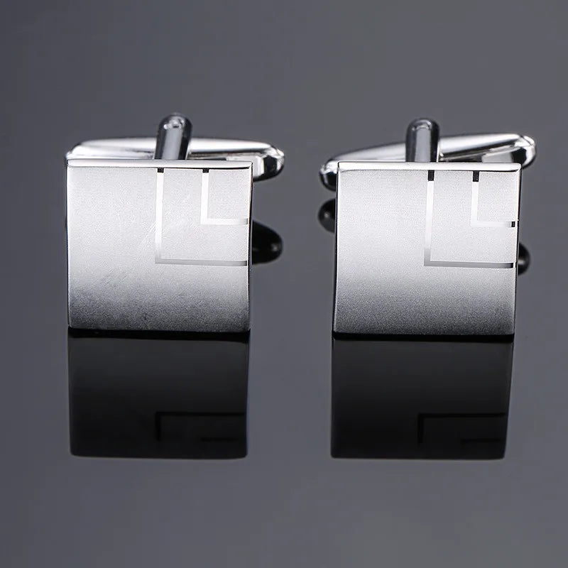 A pair of silver cufflinks featuring a square design with a geometric pattern.
