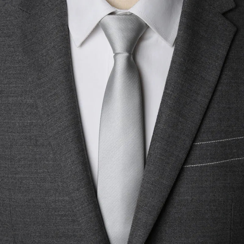 A close-up of a gray suit jacket and white shirt with a silver striped tie.