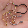 A collection of various colored faux septum nose ring hoops and clips on a skin tone background.