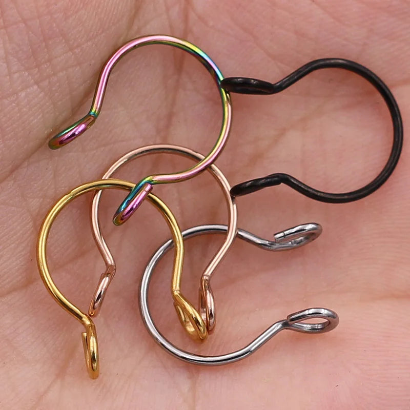 A collection of various colored faux septum nose ring hoops and clips on a skin tone background.