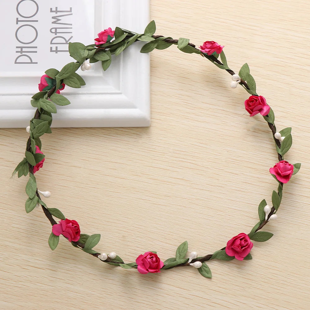 A wreath of pink and red roses and green leaves used as a bohemian flower headband for women.