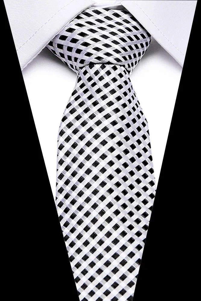 A close-up of a men's silk jacquard tie with a black and white checkered pattern worn under a white shirt.
