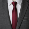 A close-up of a maroon patterned tie worn under a white shirt and gray suit jacket.