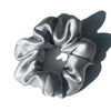 A silver silk hair scrunchie tied in a bow, shown against a white background.