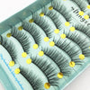 A tray of dark mink false eyelashes with gold accents displayed on a light blue background.