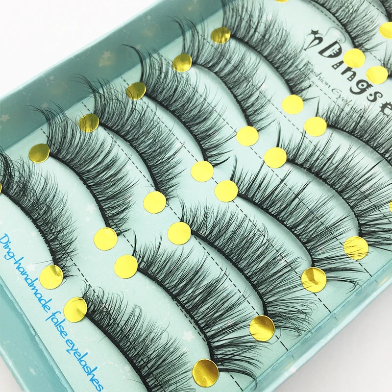 A tray of dark mink false eyelashes with gold accents displayed on a light blue background.