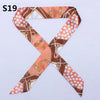 An orange and brown patterned silk headband scarf with a leopard print design