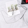 A pair of black eyeglasses with a silver star pendant attached to a chain and lanyard, resting on a white card.