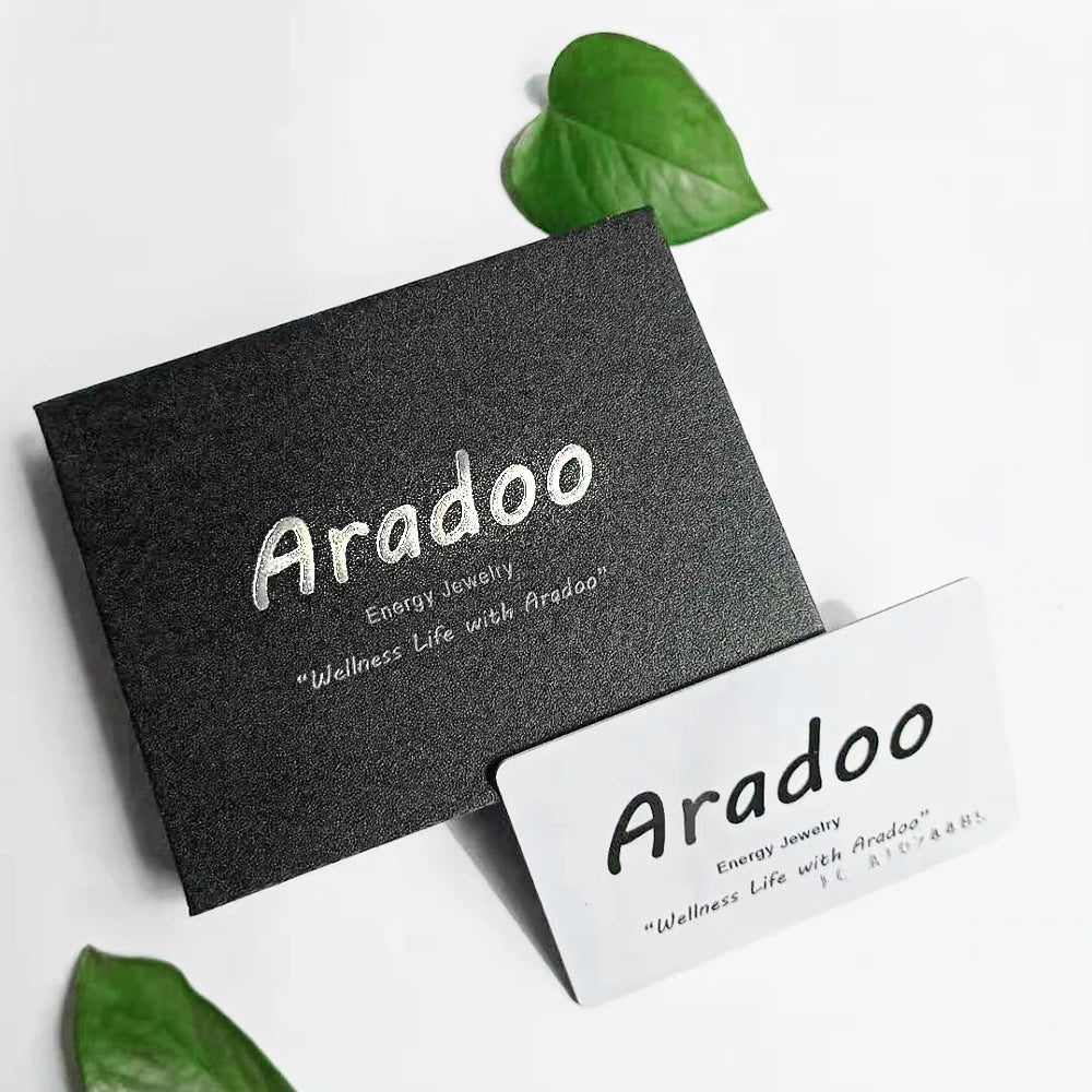 A black card with gold text and a green leaf resting on a white surface.