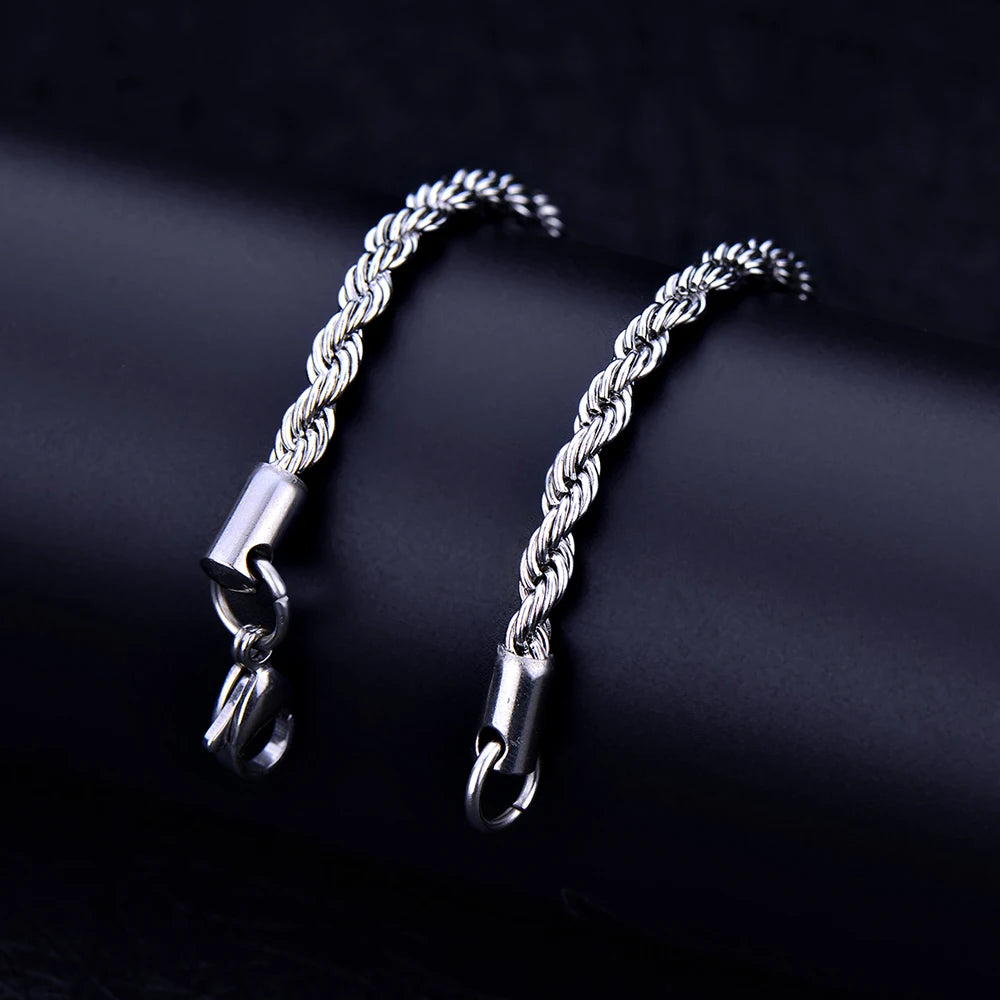 A silver stainless steel twisted rope chain bracelet laid diagonally on a dark surface.
