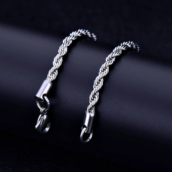 A silver stainless steel twisted rope chain bracelet laid diagonally on a dark surface.